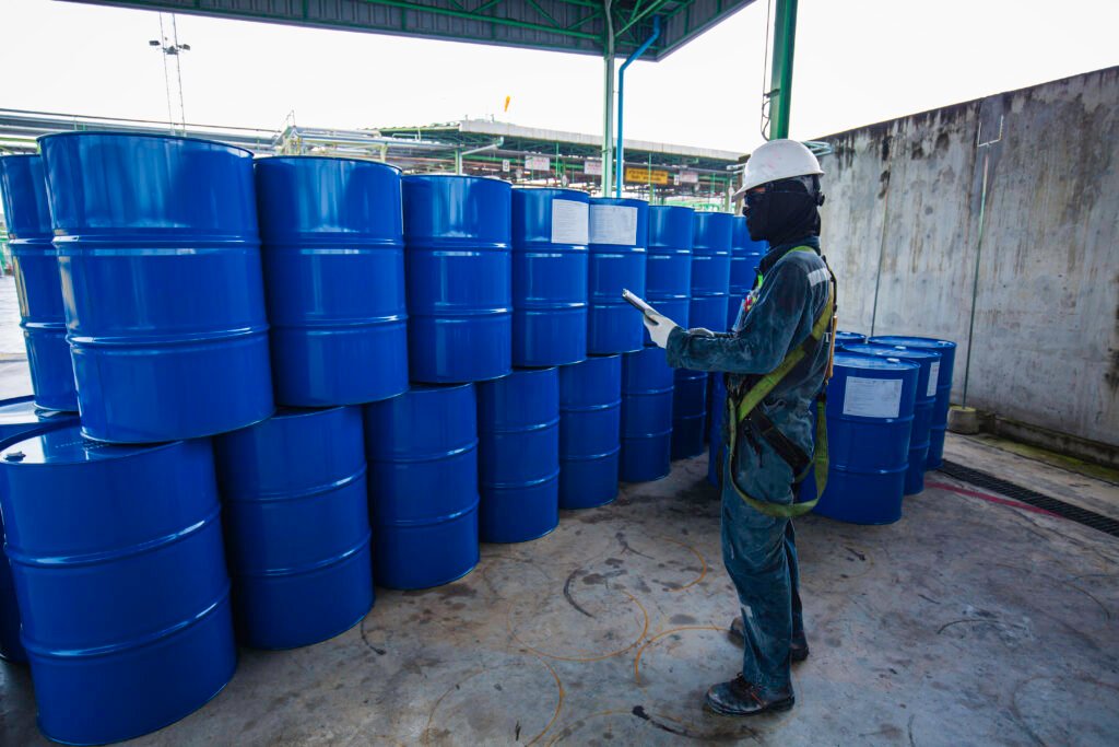 male worker inspection record drum oil stock barrels blue vertic